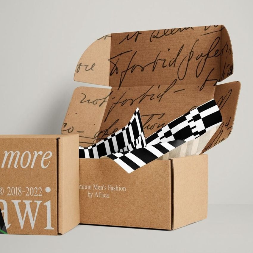 Mailing box mockup showing an open kraft box with handwritten script on the inside lid and monochrome patterned tissue paper.