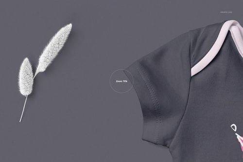 PSD mockup featuring a partial view of a baby onesie in dark gray with pale trim, placed beside soft white plants.