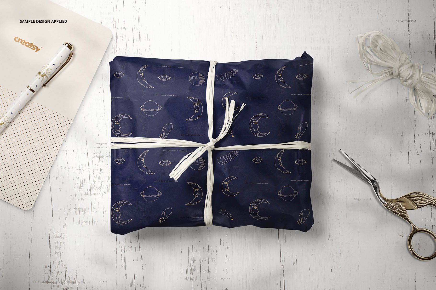 PSD mockup of gift wrapping tissue paper featuring moon and cloud motifs, tied with white string on rustic wood.