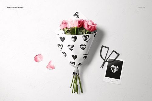 PSD mockup showing a bouquet of pink roses in decorative wrapping paper, with a monochrome card and raffia ribbon nearby.