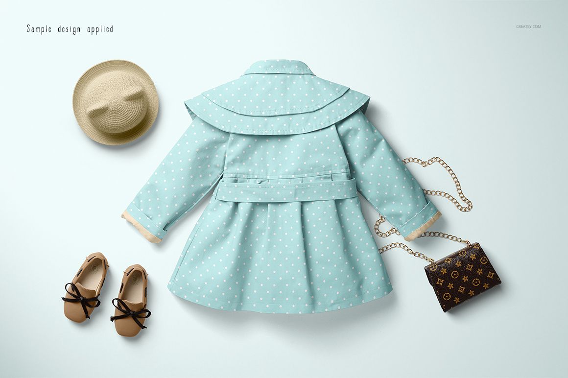 Baby coat mockup in pastel blue with white polka dot pattern, shown from above with matching accessories on a pale surface.