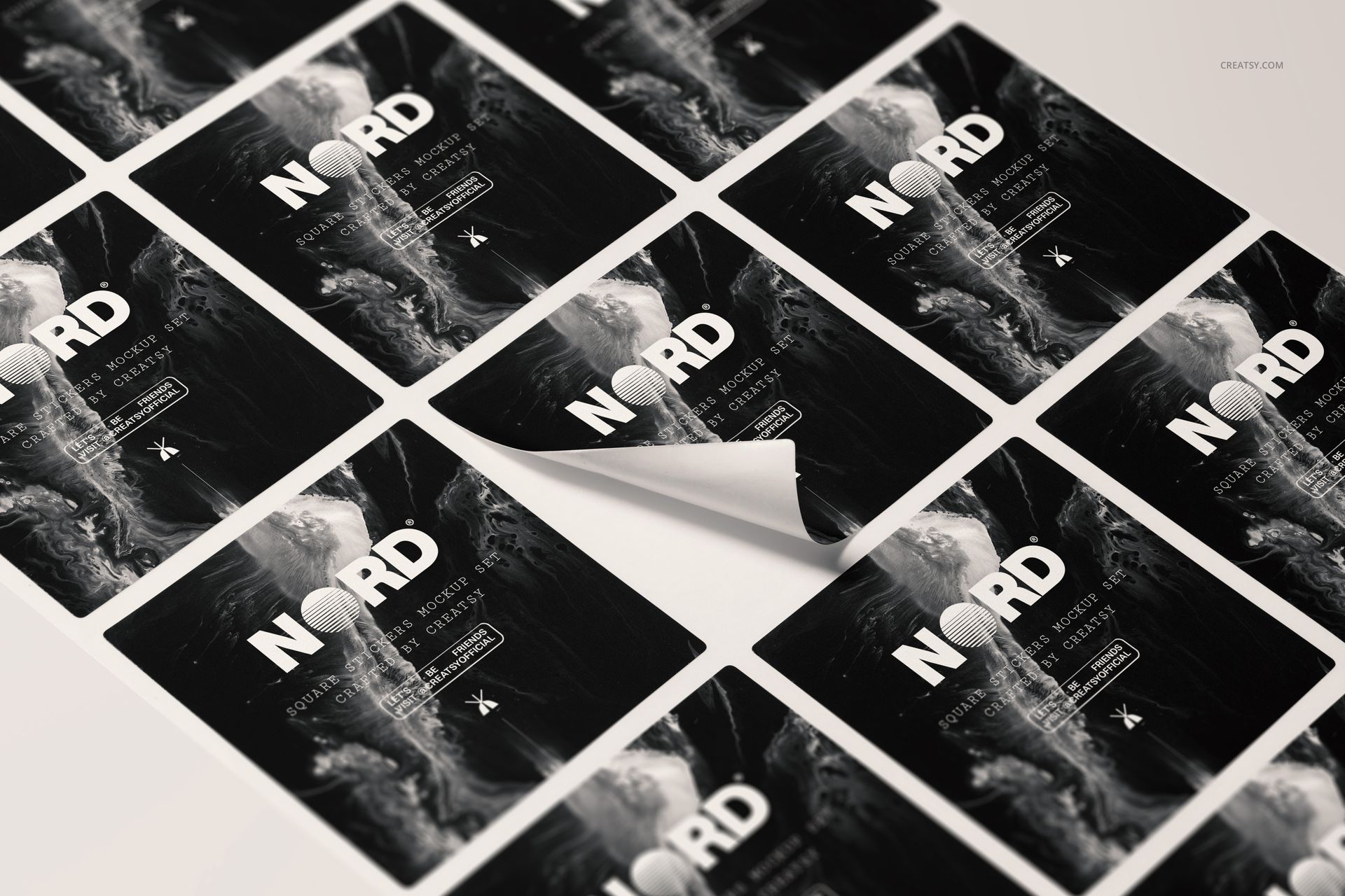 Square stickers arranged in a grid pattern, featuring a monochrome abstract design and bold white text, viewed at an angle.