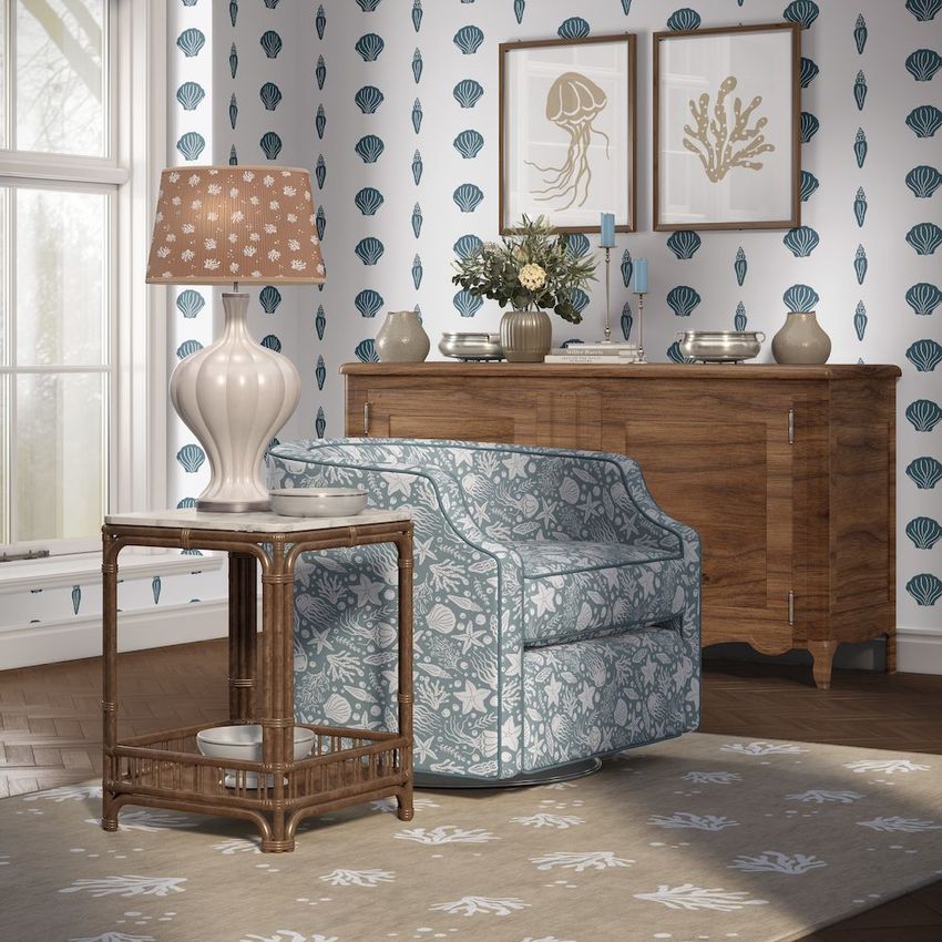 Living room wallpaper mockup featuring a patterned armchair, wooden side table with lamp, and coastal decor accents.