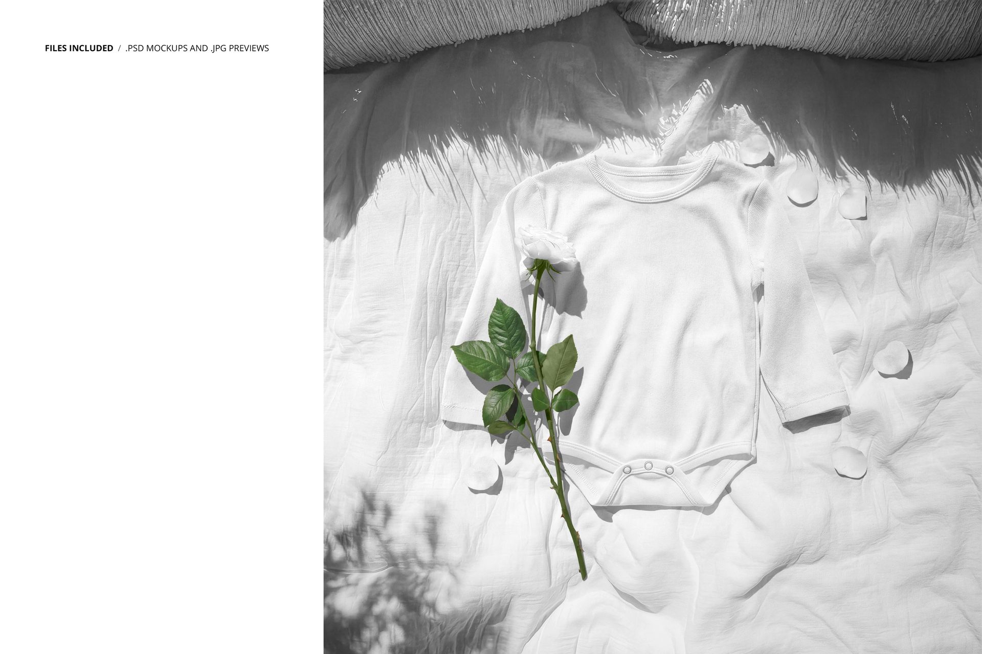 Front view of a white baby growsuit mockup lying on a white fabric surface with a rose and scattered petals.