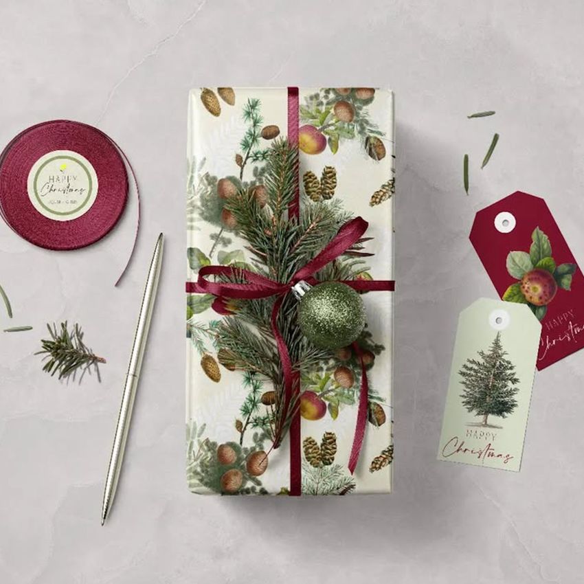 Christmas gift wrapping paper packaging mockup featuring a rectangular box with festive botanical patterns, red ribbon, and ornament.