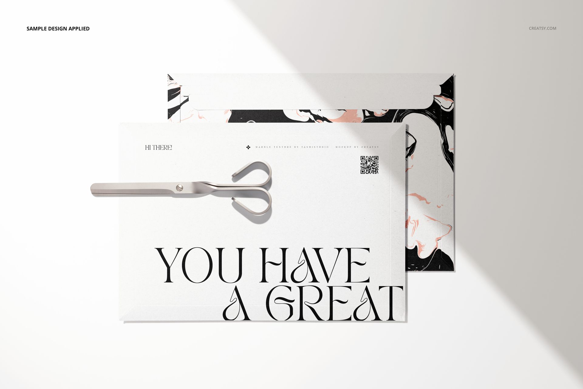 Mockup of tear strip envelopes featuring marble-like designs and large typography, shown with scissors on a white surface.