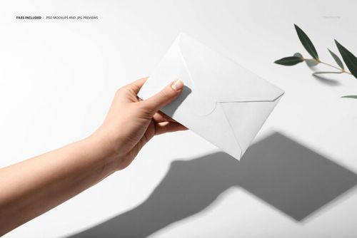 White envelope mockup with sticker closure held in a hand, light shadow and leafy branch in the background.