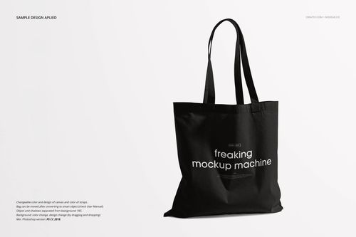 Front view of a black tote bag mockup with long handles and white lettering, set on a minimal white backdrop.