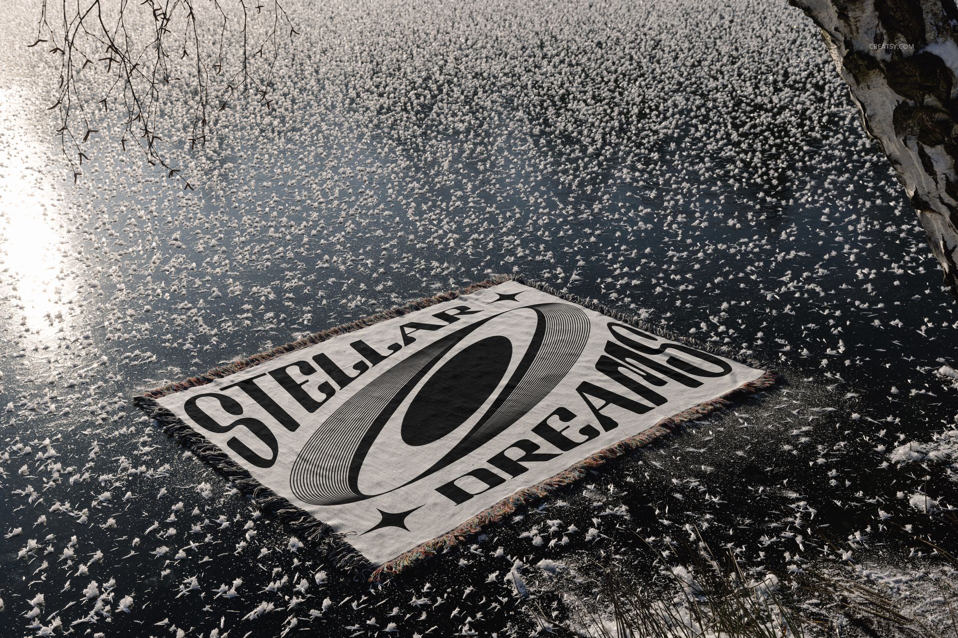 Winter-themed blanket mockup featuring a geometric pattern and large text, laid out on icy water near a snowy shore.