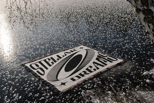 Winter-themed blanket mockup featuring a geometric pattern and large text, laid out on icy water near a snowy shore.