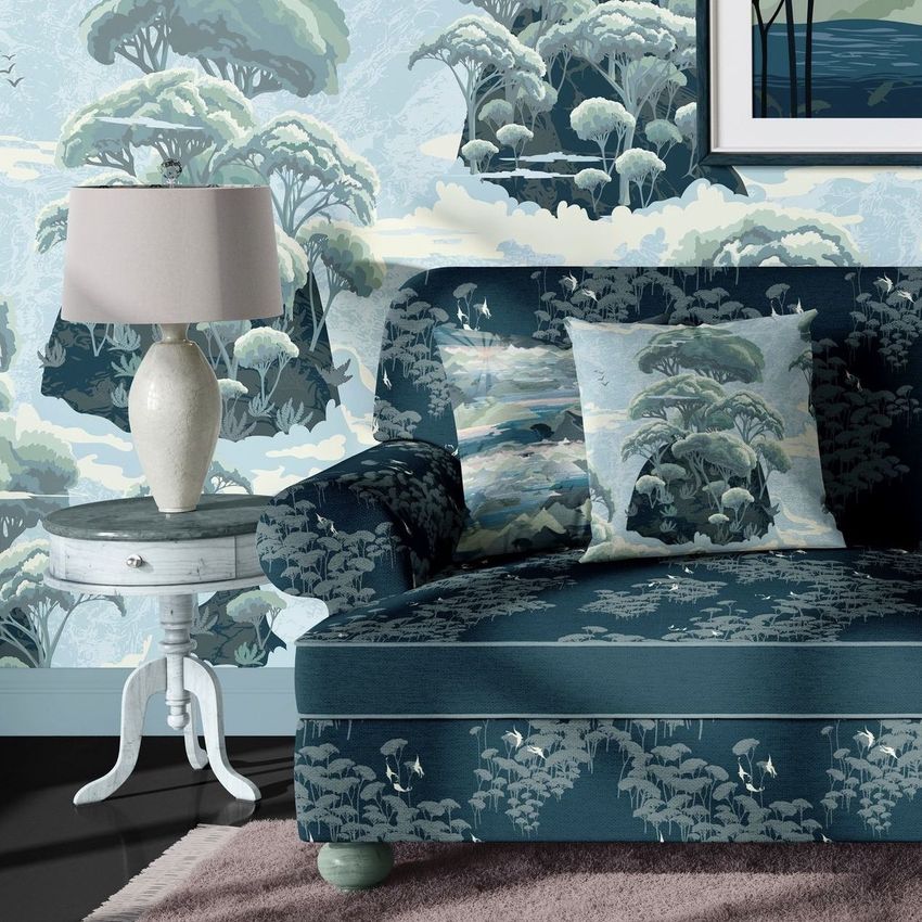 Sofa mockup with patterned upholstery and matching pillows, set against a scenic wallpaper with trees in blue and green tones.