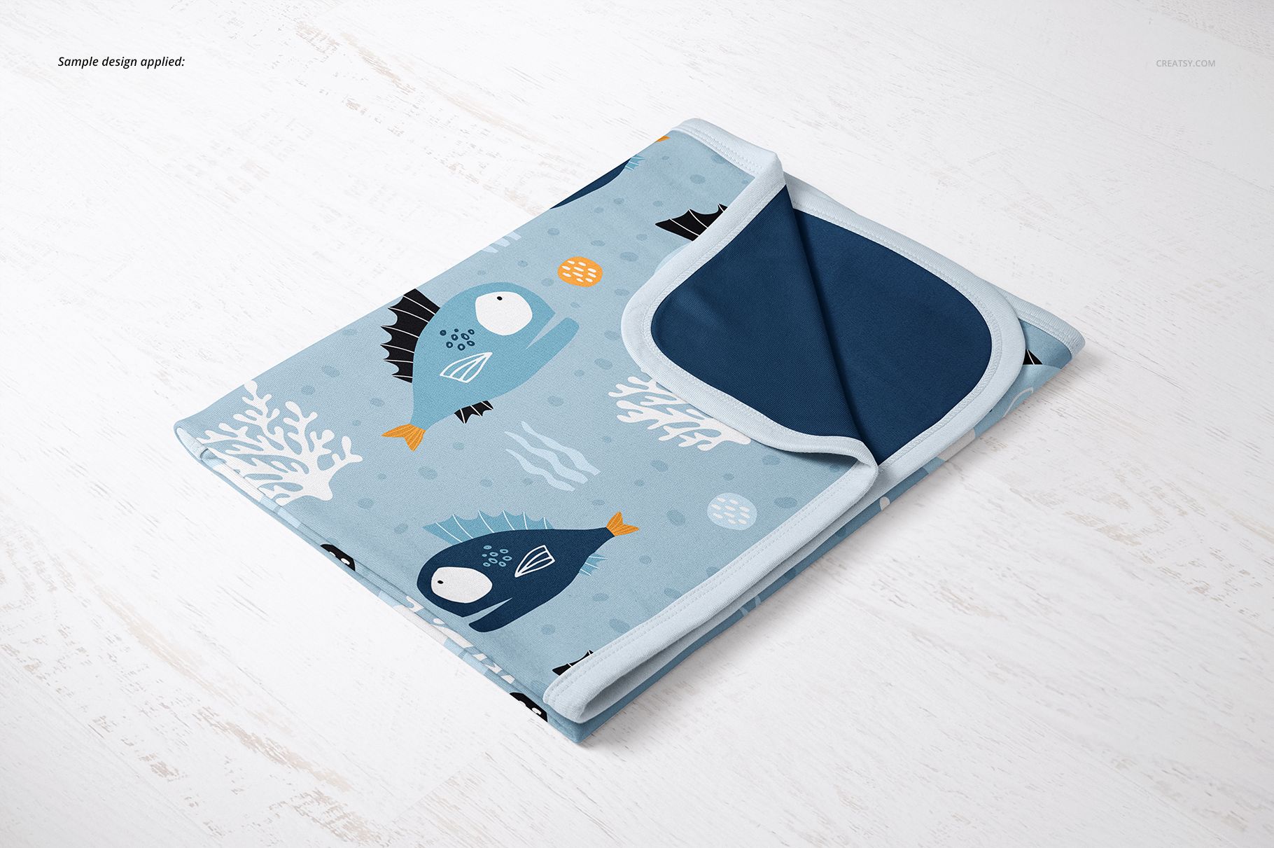 Cotton baby blanket mockup featuring playful aquatic design, folded neatly with dark blue reverse side visible.