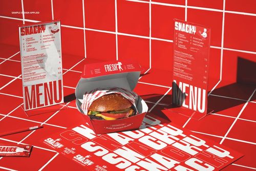 Front view of a burger bar menu display mockup with red packaging, burger box, and printed menus on a tiled surface.