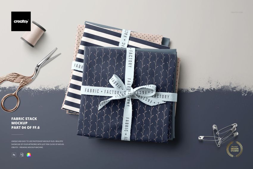 Top view of a fabric stack mockup featuring assorted folded textiles with ribbon, scissors, and sewing props.