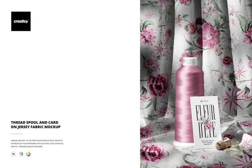 PSD mockup showing a thread spool and card on draped jersey fabric with a detailed pink flower pattern.