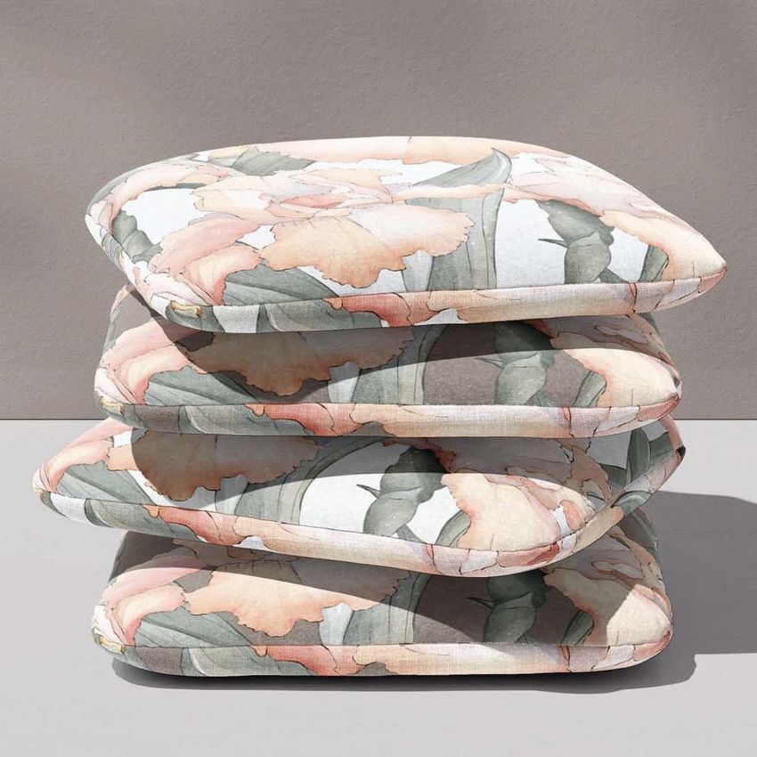 Stack of four square chair cushions with a soft floral pattern in pastel pink, green, and beige on a neutral background.