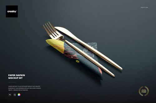 Colorful patterned paper napkin mockup featuring gold cutlery on a matte dark background, shown from above.