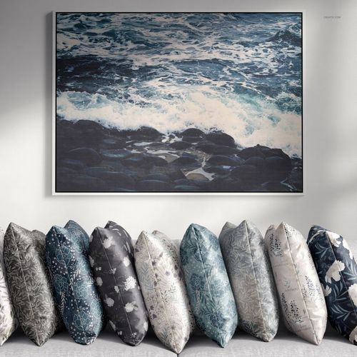 Mockup showing multiple velvet pillows with botanical and abstract designs, positioned under a framed seascape print.