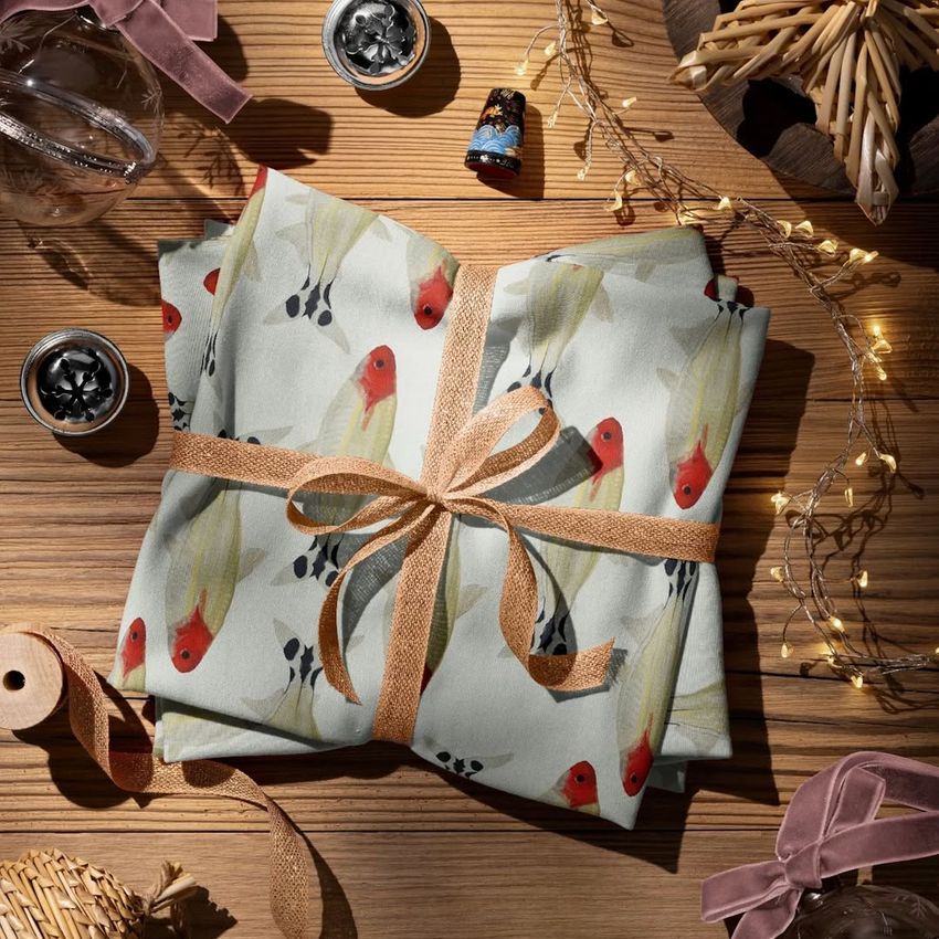 Jersey fabric mockup with a watercolor fish print, neatly tied and set among holiday decor on a wooden surface.