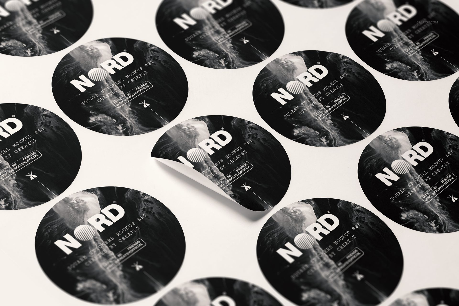 Round stickers with monochrome abstract designs arranged on a flat surface, one sticker partially peeled up.