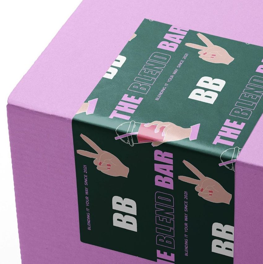 Closeup of a mailing box mockup with a purple textured surface and a dark green sticker featuring hand illustrations and bold text.