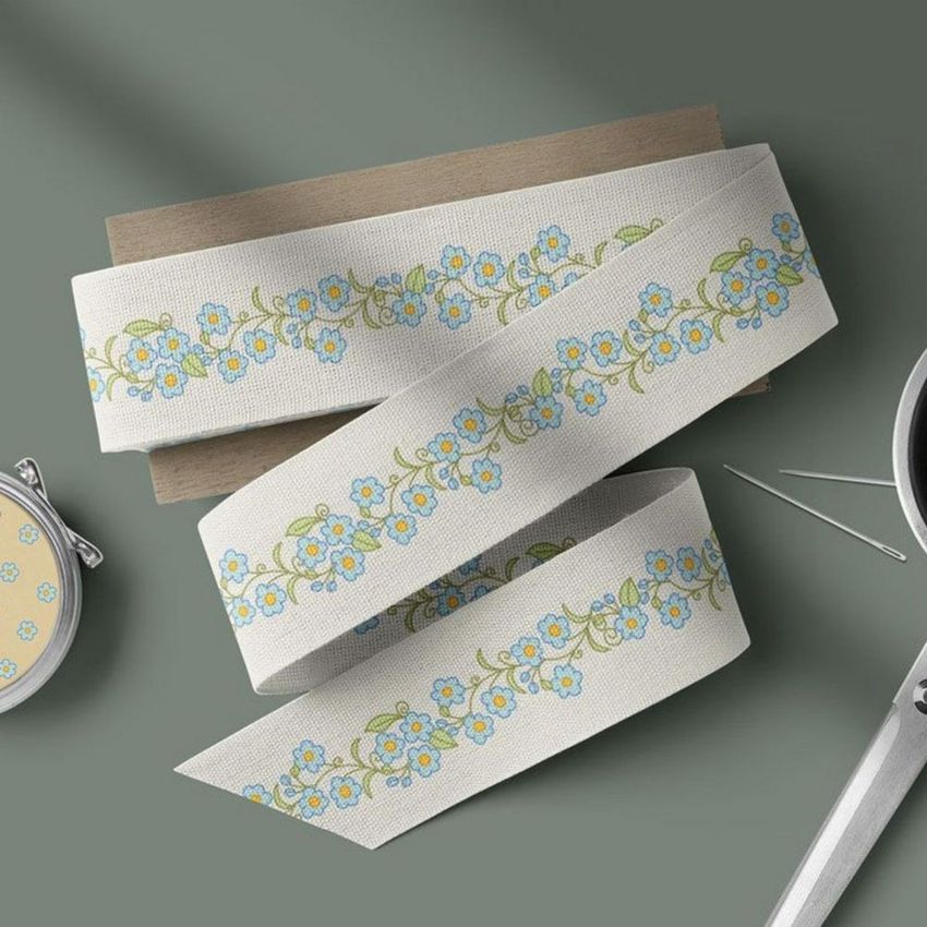 Cotton ribbon mockup featuring a floral pattern in blue and green, displayed on a wooden board with sewing tools nearby.