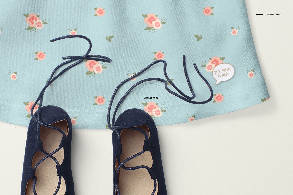 Close-up front view of a baby dress mockup with a blue floral pattern, paired with navy blue baby shoes on a light background.