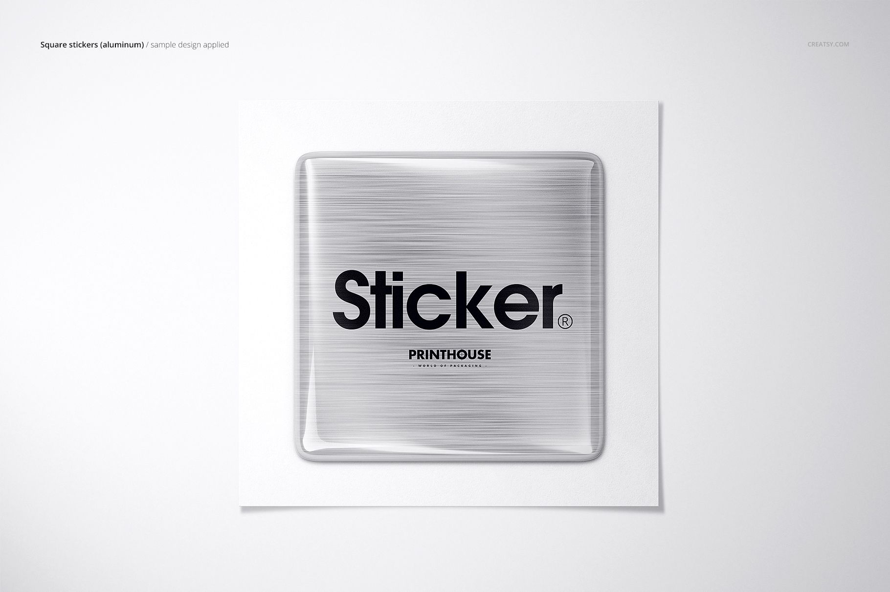 Close-up of a square metallic epoxy dome sticker mockup featuring bold black lettering, displayed on a white surface.