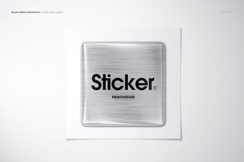 Close-up of a square metallic epoxy dome sticker mockup featuring bold black lettering, displayed on a white surface.