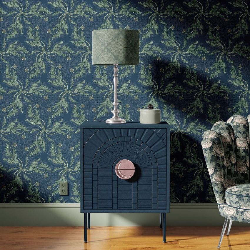Drum lamp shade mockup displayed on a decorative lamp atop a dark blue cabinet, with floral wallpaper and an armchair.