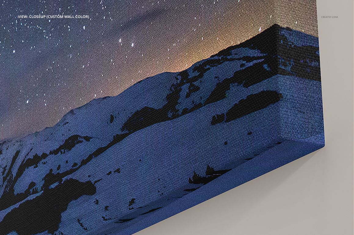 Close-up view of a canvas print mockup showing a starry night sky and snowy mountains, angled perspective.