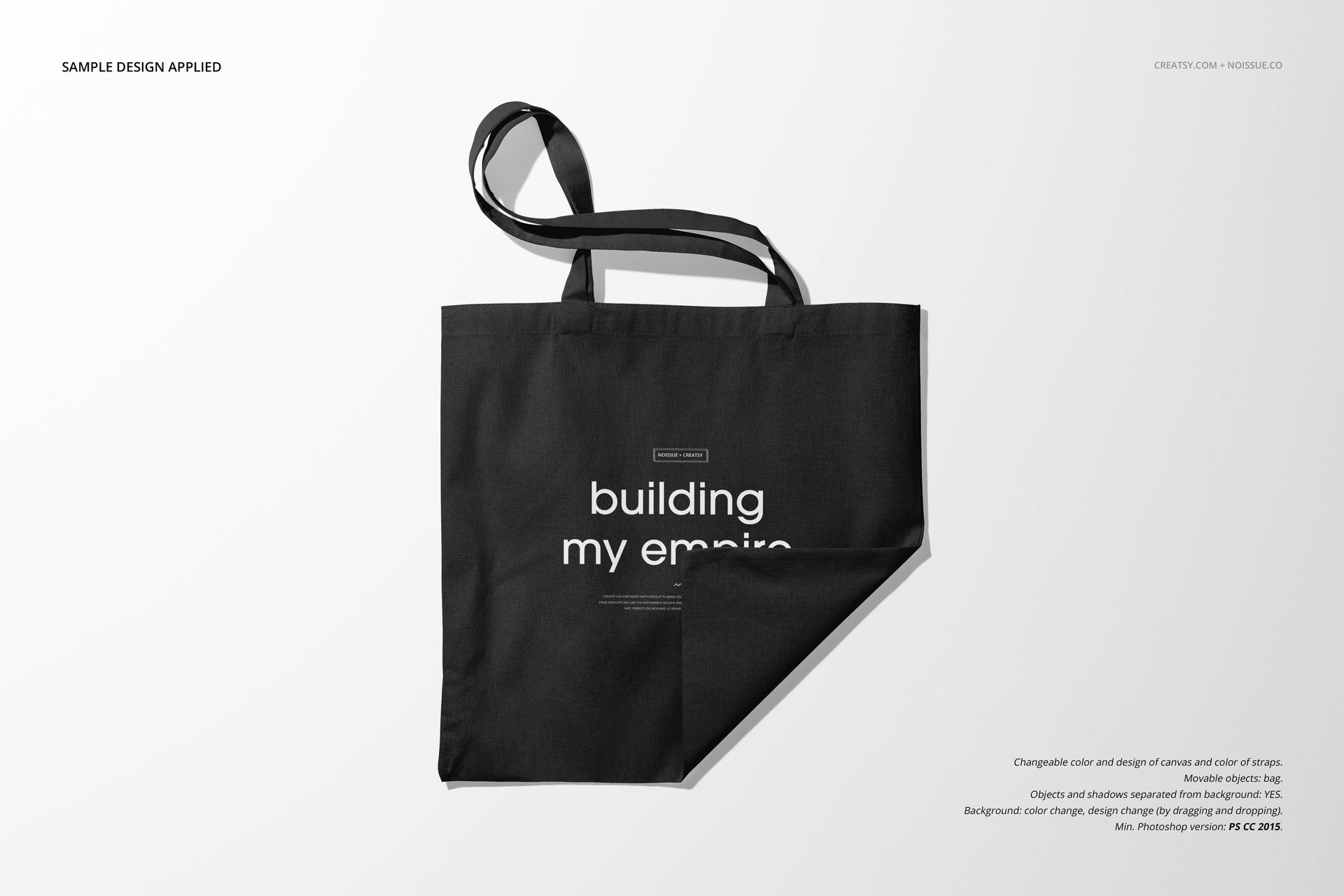 Front view of a black tote bag mockup with a folded corner and centered white lettering on a plain surface.