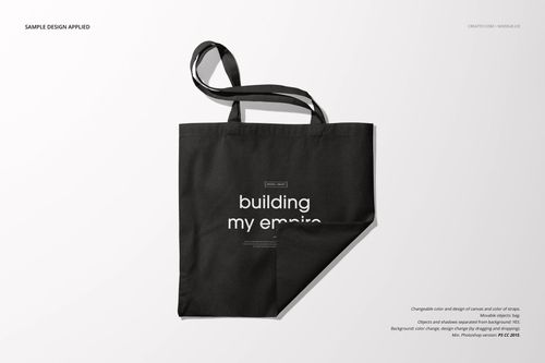 Front view of a black tote bag mockup with a folded corner and centered white lettering on a plain surface.