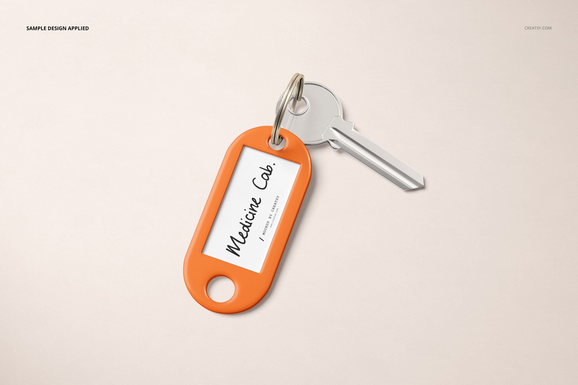 Orange key tag mockup with a silver key attached, displayed on a light beige surface in a top view layout.