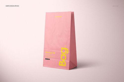 PSD mockup showing a single pink paper lunch bag with yellow lettering, displayed in a clean, neutral setting.