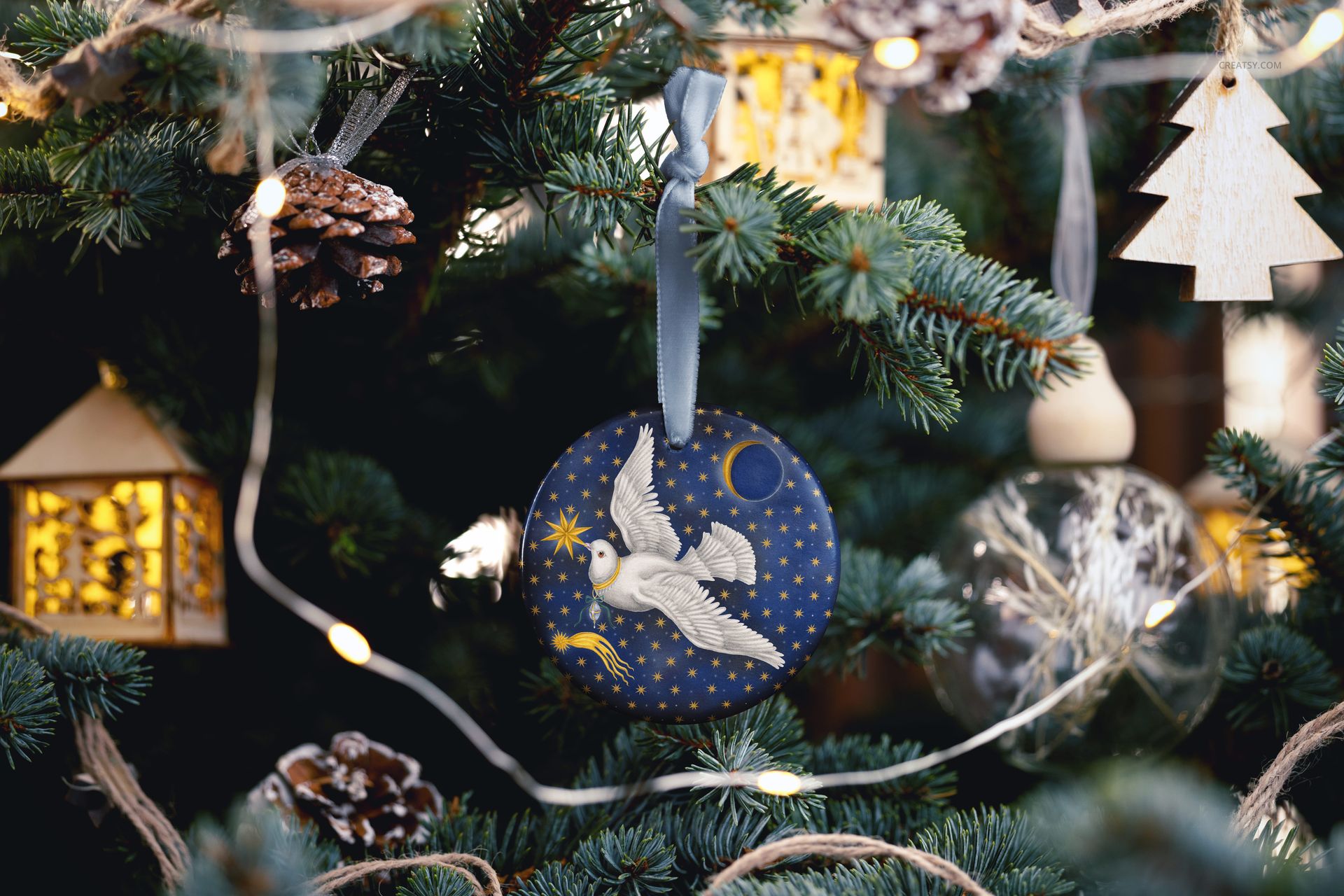 Handmade round ornament mockup featuring a celestial dove design and velvet ribbon, displayed on a festive pine tree.