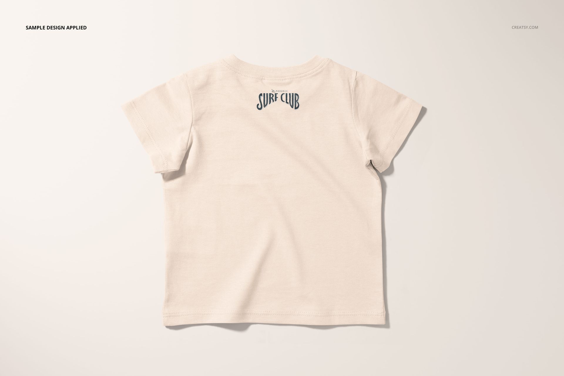 PSD mockup of a short-sleeve infant t-shirt in soft beige, shown from the rear with a subtle graphic on the upper back.
