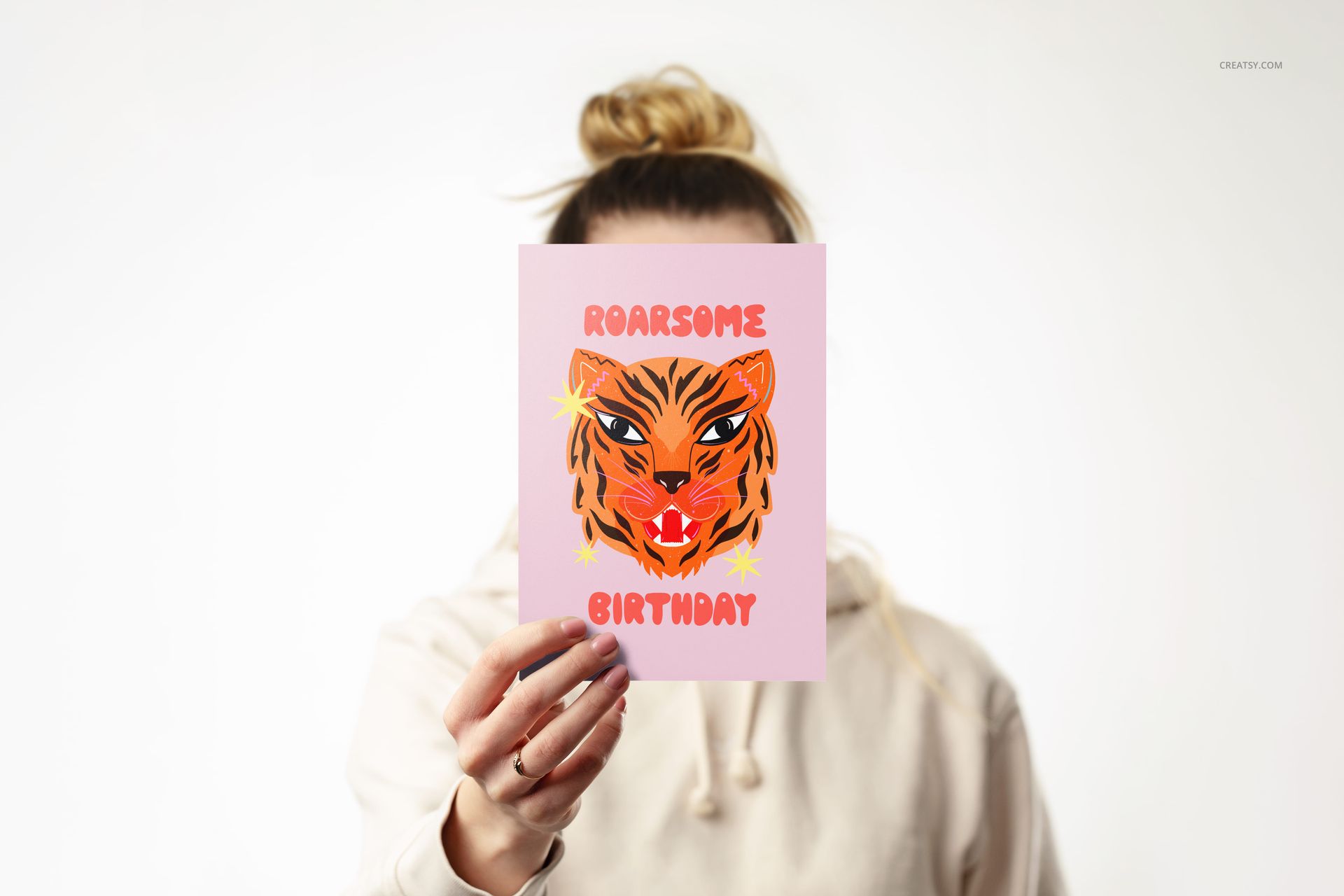 A5 card mockup held upright against a white background, featuring a pink card with a tiger illustration and birthday text.