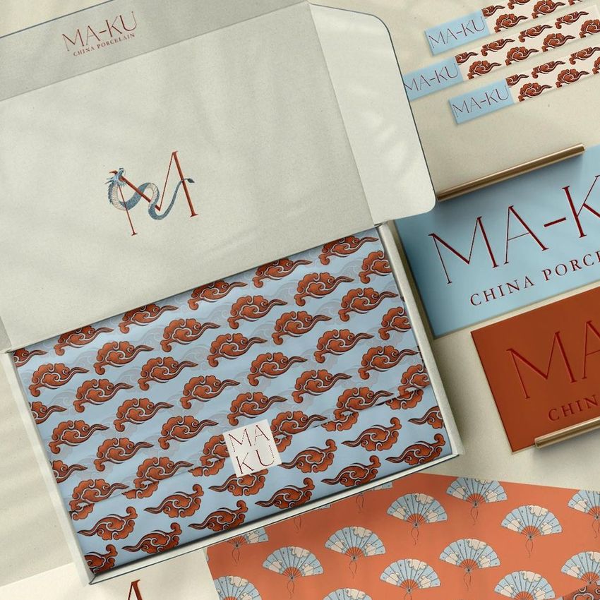 Mailing box mockup featuring an open box with patterned tissue paper, branded cards, and decorative fan motifs in blue and orange tones.