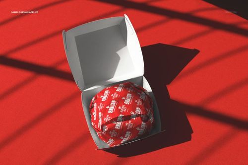 PSD mockup showing an open burger box and a burger wrapped in red paper, set against a red surface with diagonal shadows.