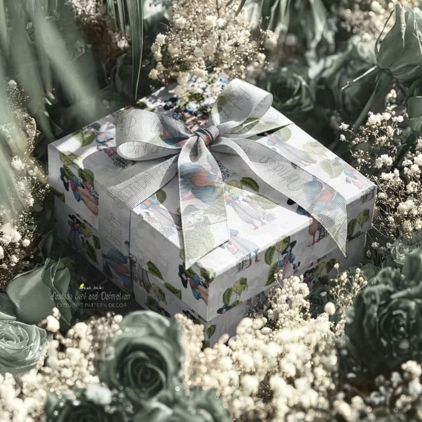 Square gift box mockup with a patterned design and large gray ribbon, surrounded by red and white roses and greenery.
