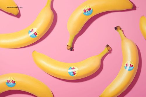 Top view of multiple bananas featuring round stickers, arranged on a vibrant pink surface for a mockup scene.