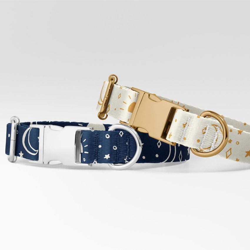 Dog collar mockup showing two collars with celestial patterns, one in navy blue and one in cream, on a light gray background.