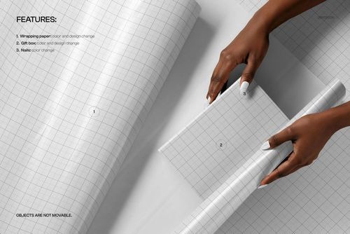 Hands wrapping a rectangular gift box with white grid-patterned wrapping paper, viewed from above on a flat surface.