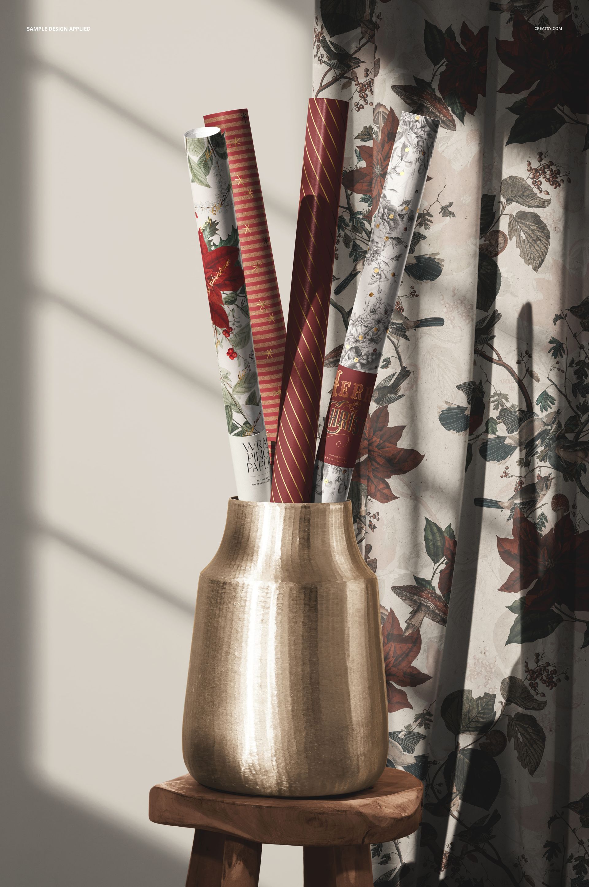 PSD mockup showing assorted wrapping paper rolls in a gold-colored vase, set against a softly lit interior with botanical decor.