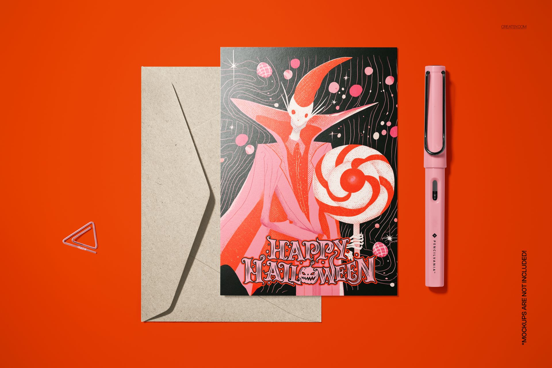 Halloween card mockup with vintage monster illustration and lollipop, shown with envelope and pink pen on orange surface.
