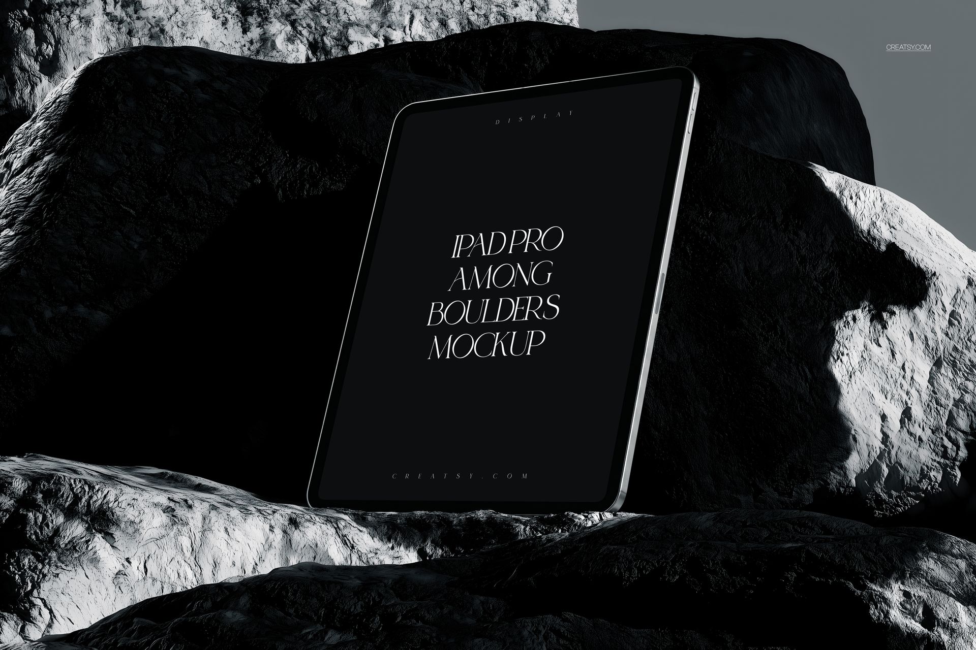 iPad Pro PSD mockup displayed vertically against rugged boulders, featuring a minimalist black screen design.