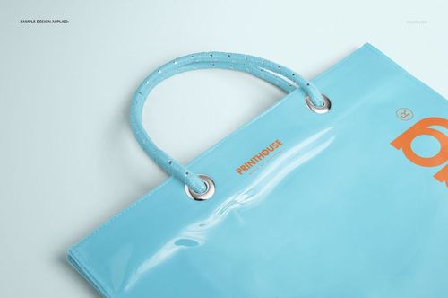Glossy light blue vinyl PVC tote bag mockup featuring sturdy handles and metallic grommets, photographed from above.