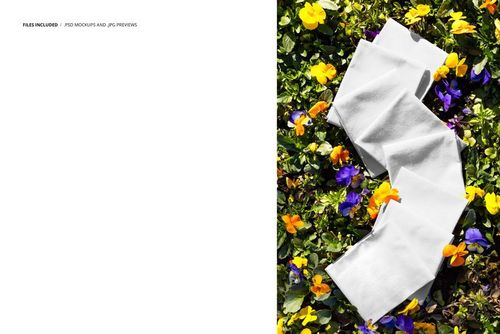 Multiple white fabric pieces displayed on blooming pansies, photographed from above in a PSD mockup scene.