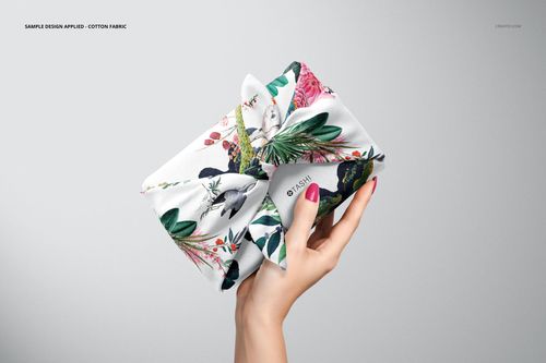Furoshiki fabric wrap mockup featuring a floral and leaf design, displayed in a hand against a plain backdrop.